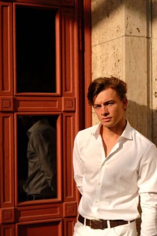 A white open-collar shirt worn against a sunlit wall